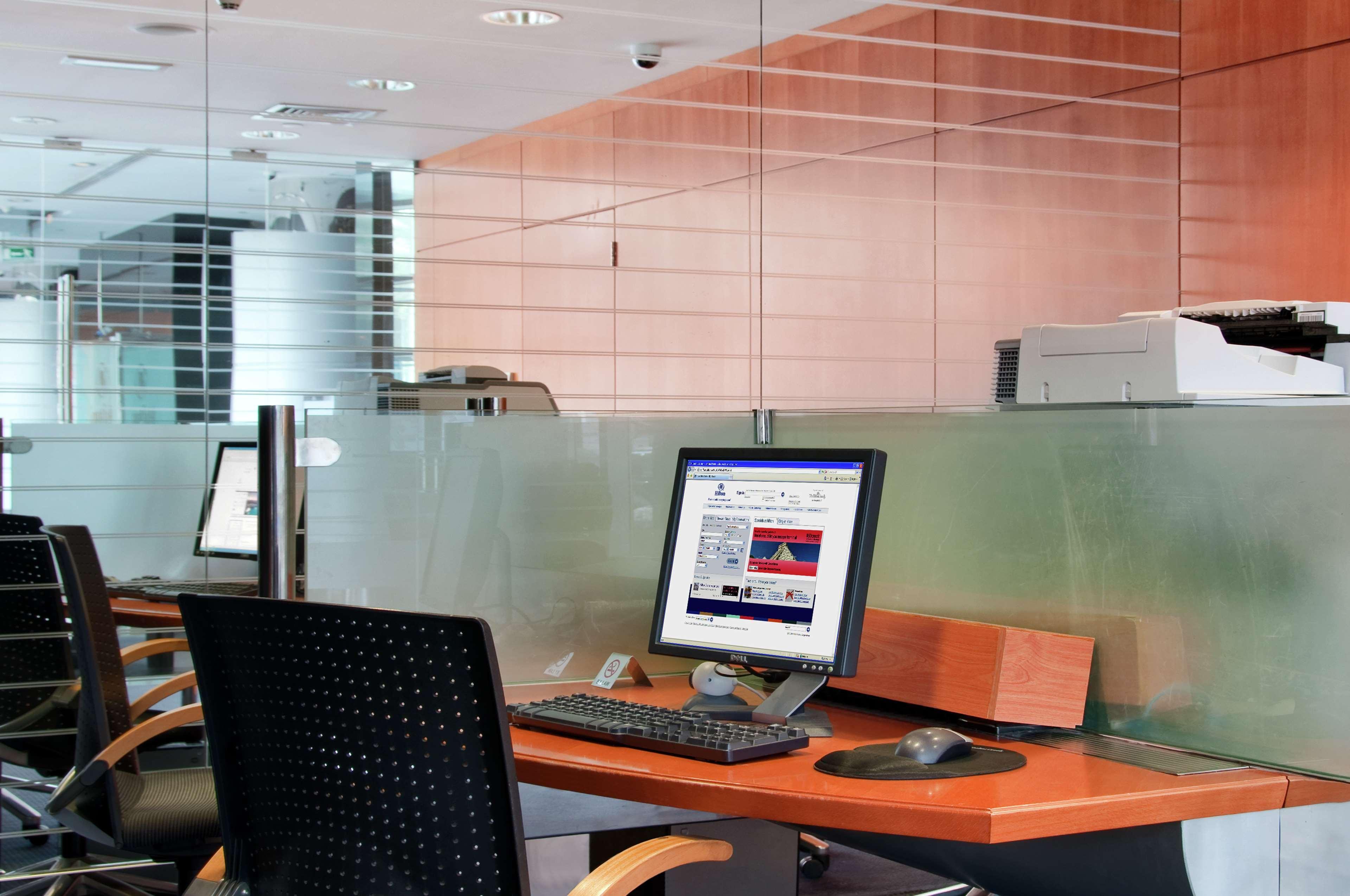 Golden Sands Boutique Hotel-Dubai Creek Ανέσεις φωτογραφία The photo showcases a modern office space featuring a few workstations. Each workstation includes a computer monitor, keyboard, and mouse, set on a sleek wooden desk. The decor has a minimalist style with glass partitions and wooden paneling, contrib
