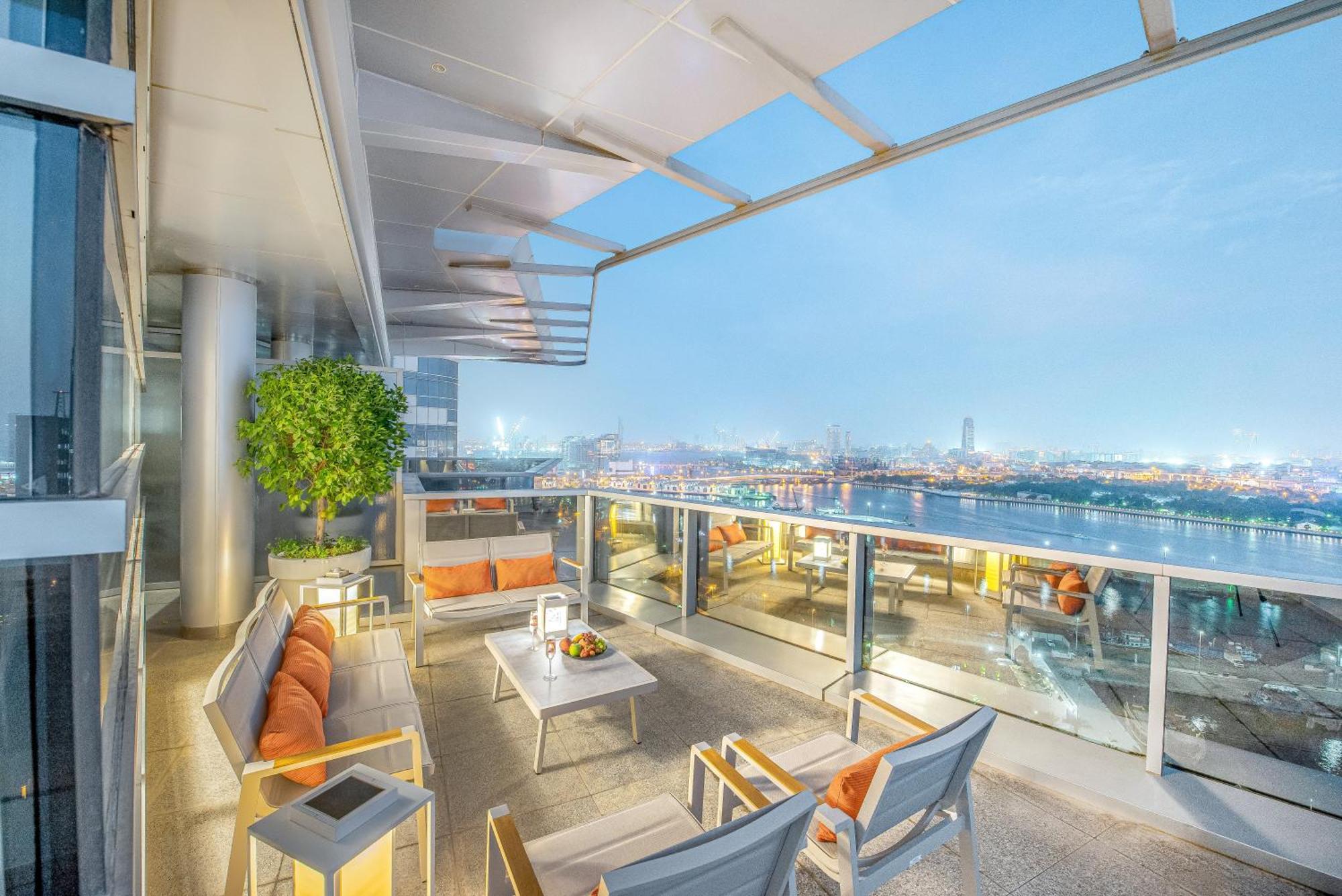 Golden Sands Boutique Hotel-Dubai Creek Εξωτερικό φωτογραφία The photo depicts a stylish balcony space with a modern design. It features outdoor seating consisting of several chairs and a table, all arranged to provide a comfortable area for relaxation. The seating has soft cushions in warm colors, and the tab