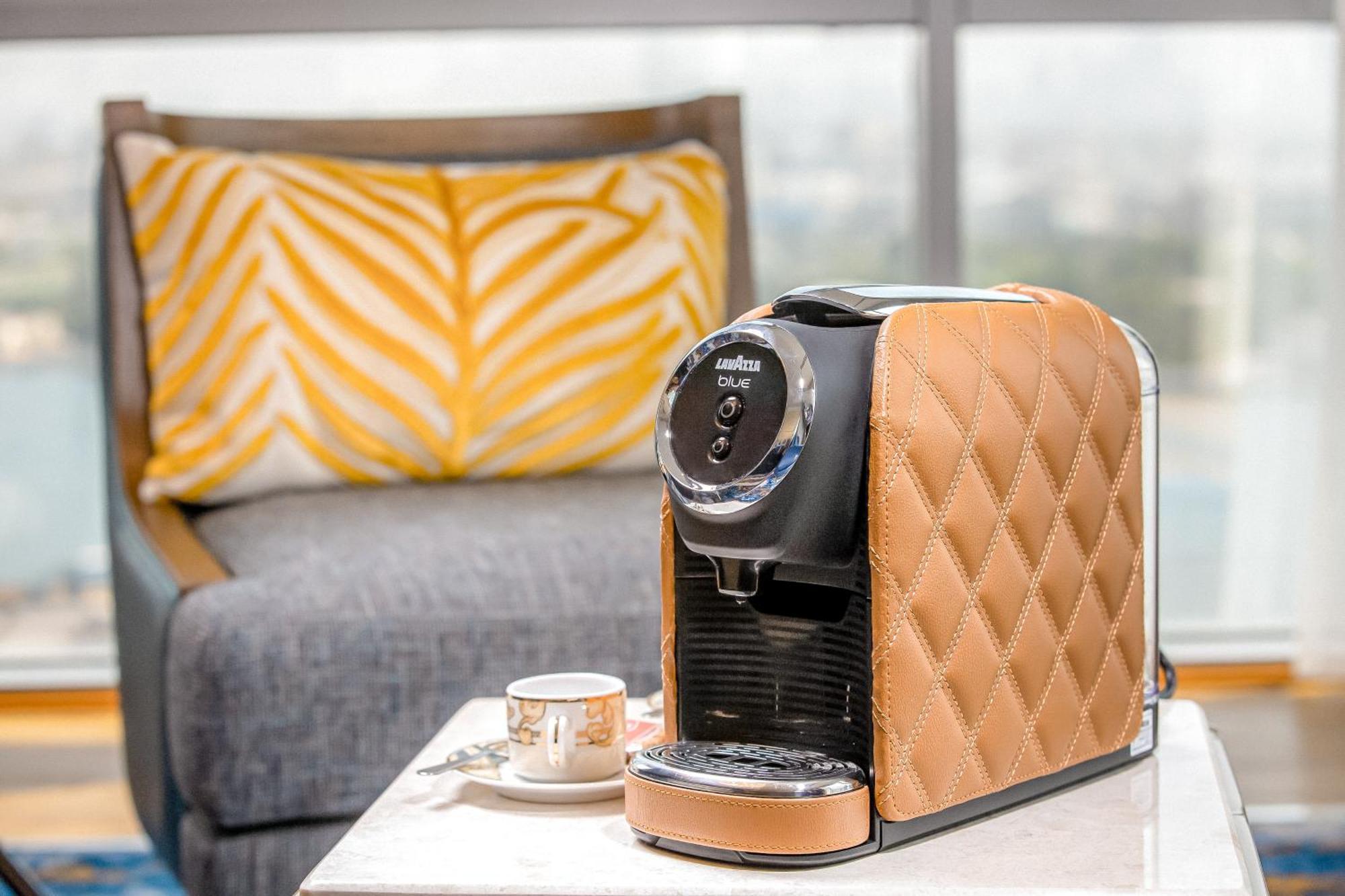 Golden Sands Boutique Hotel-Dubai Creek Εξωτερικό φωτογραφία The photo shows a stylish coffee machine with a chic design, featuring a quilted texture in a tan or beige color on one side. It's placed on a light-colored table next to a small coffee cup, which suggests it’s ready for use. In the background, there